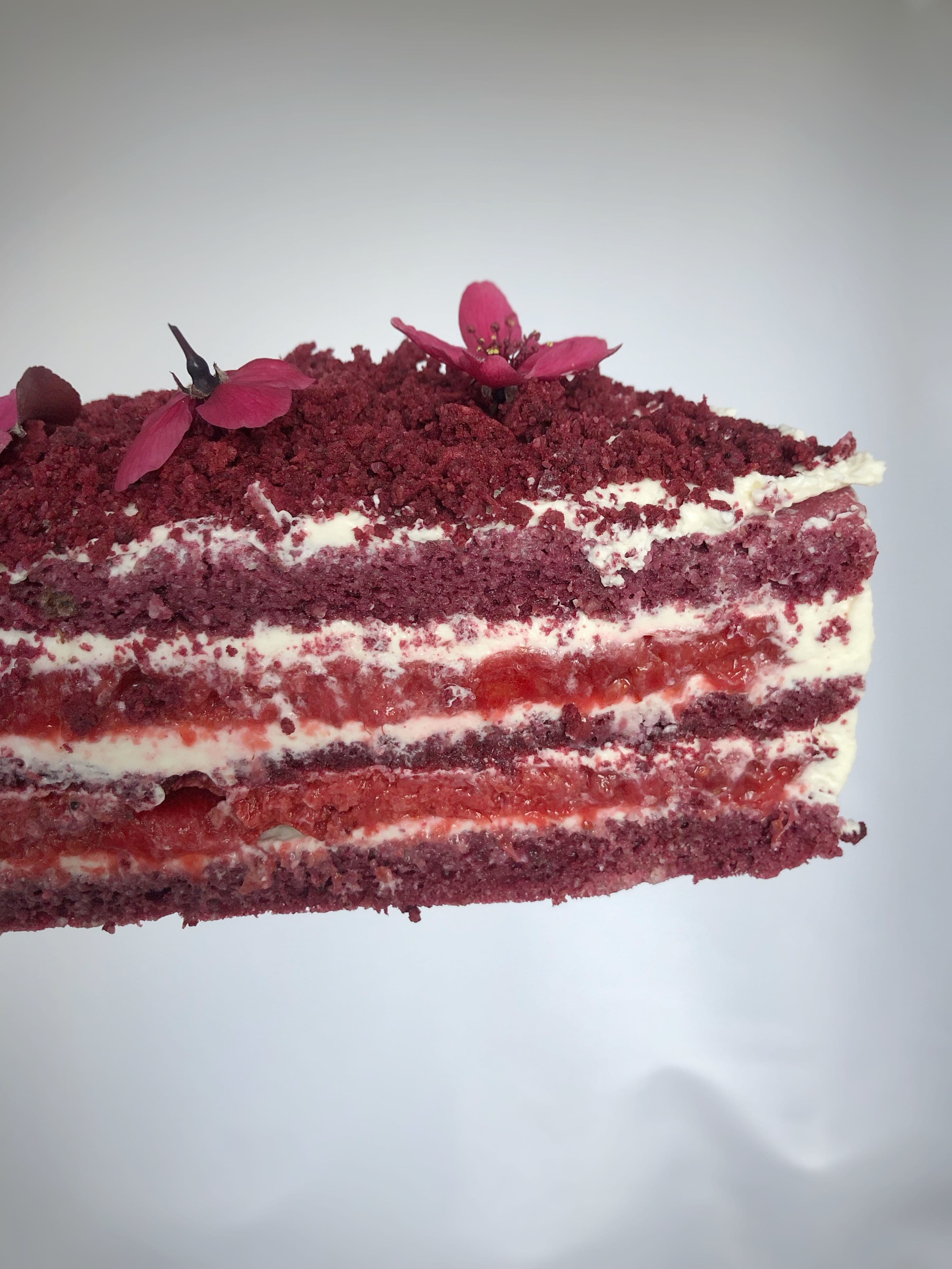 Velvet Alchemy keto cake, layered with cream and edible flowers